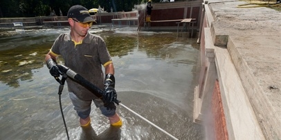 Schoonmaken van de fonteinbekkens met een heetwater-hogedrukreiniger Een Kärcher-technicus staat in het water om de binnenwanden van de cascade schoon te spuiten.