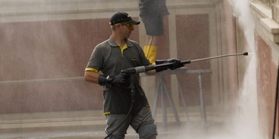 Het herstellen van de originele glans van het rode en grijze marmer Technicus verwijdert kalk- en algafzettingen van de marmeren bronwand van de cascade.