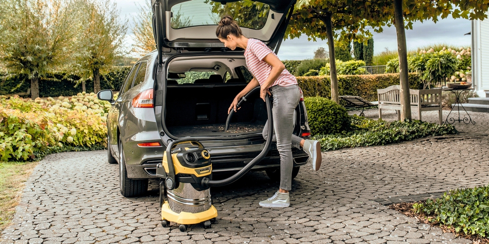 Persoon die een auto schoonmaakt met een Kärcher water-stofzuiger Persoon die een auto schoonmaakt met een Kärcher water-stofzuiger