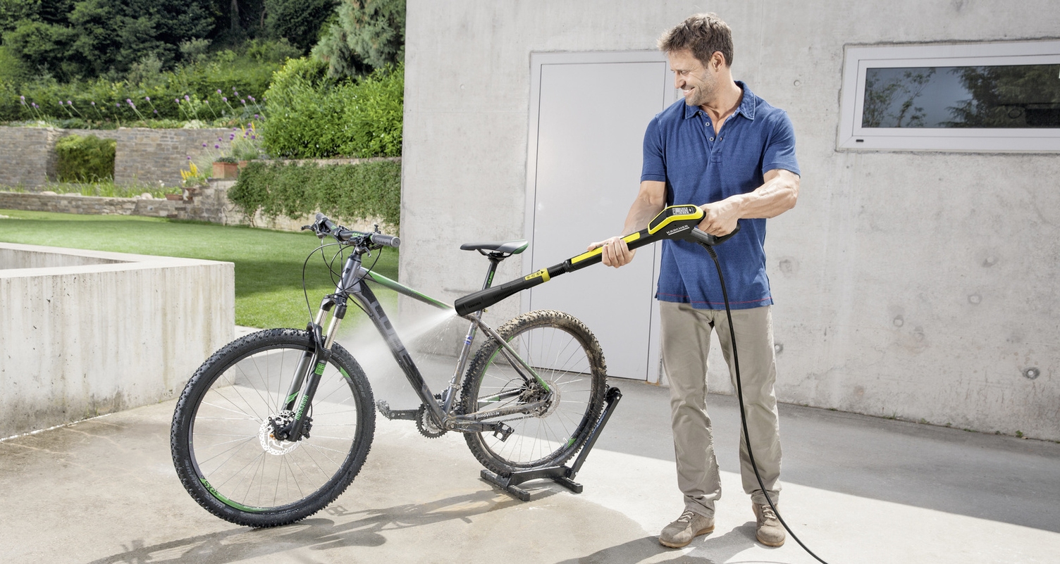 Un homme nettoie son vélo avec un nettoyeur haute pression Kärcher