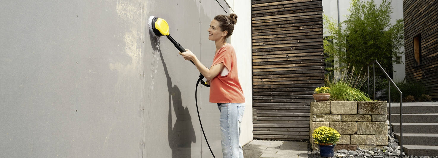 Nettoyer la porte de garage Une femme nettoie une porte de garage avec une brosse de lavage Kärcher