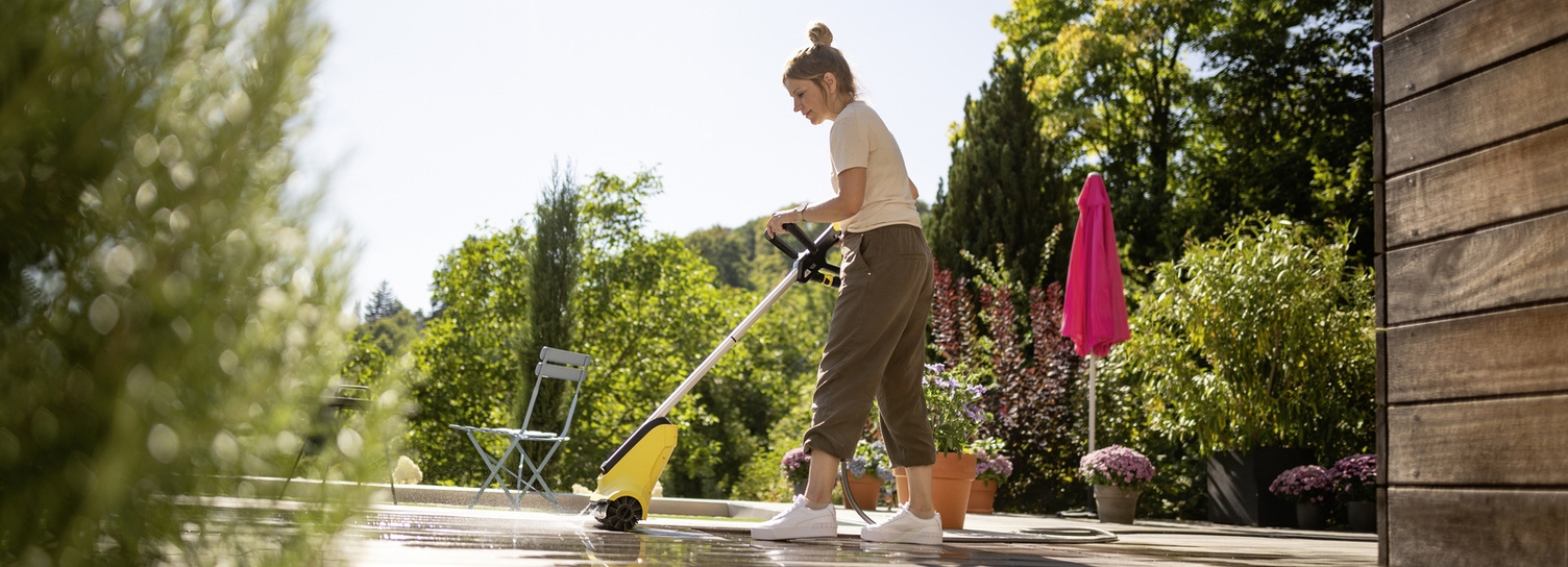 Nettoyer une terrasse en bois Une femme nettoie une terrasse en bois sur un toit avec un nettoyeur de terrasse Kärcher