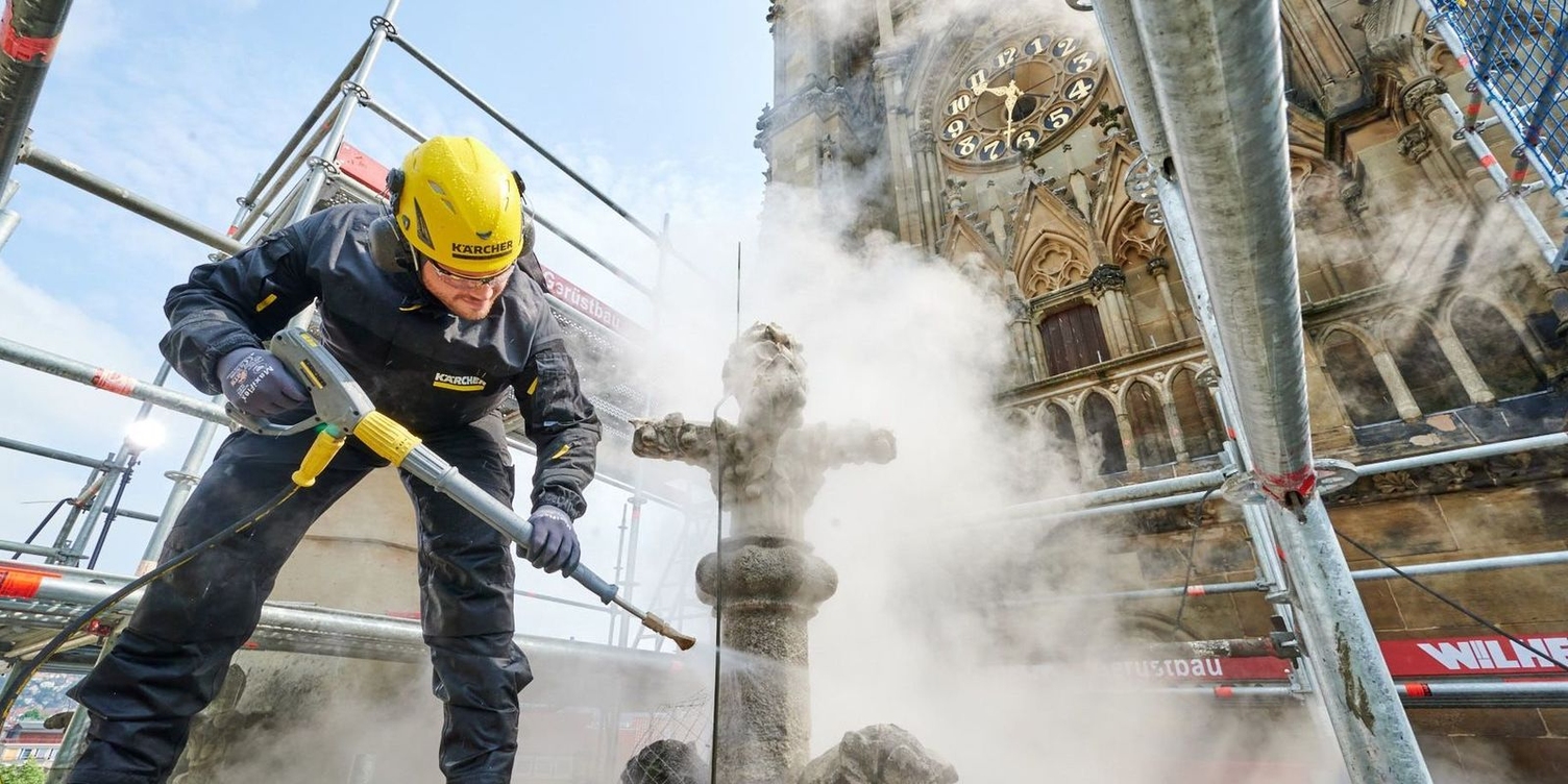 Vor dem Kirchturm reinigt Kärcher-Mitarbeiter Alexander Kendel eine Fiale mit der Dampfstufe eines Heisswasser-Hochdruckreinigers