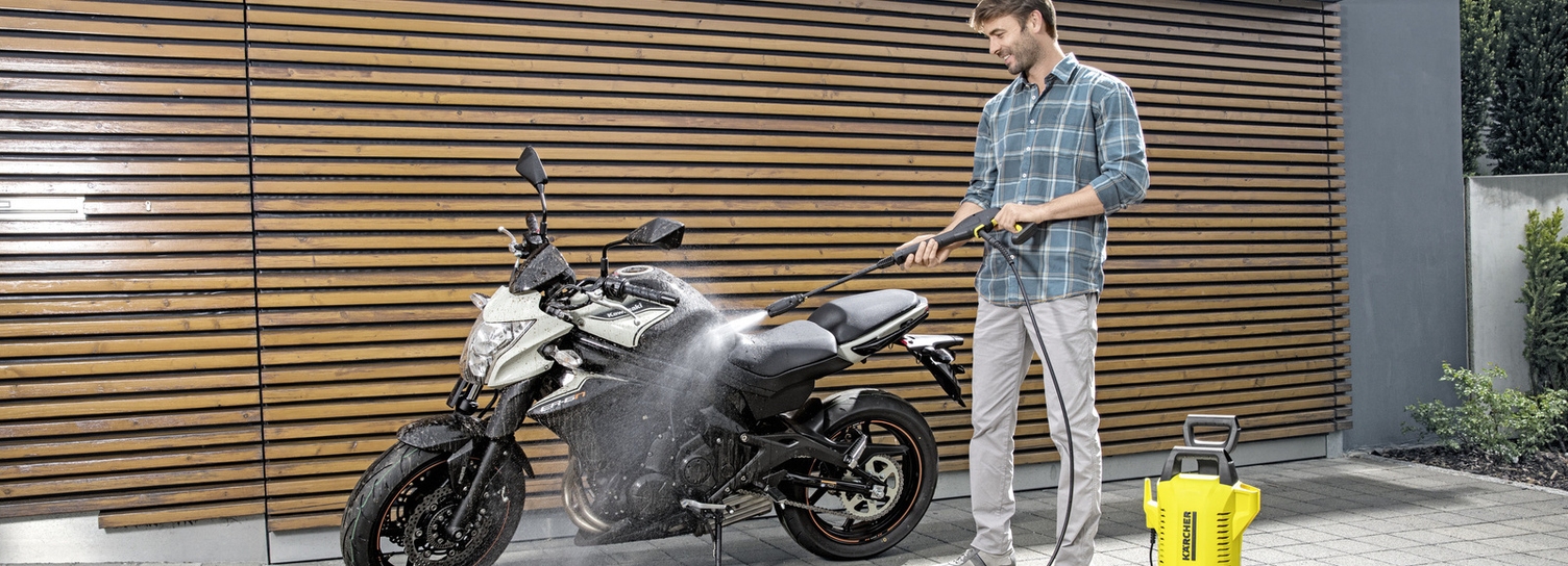 Ein Mann reinigt sein Motorrad mit einem Kärcher Hochdruckreiniger