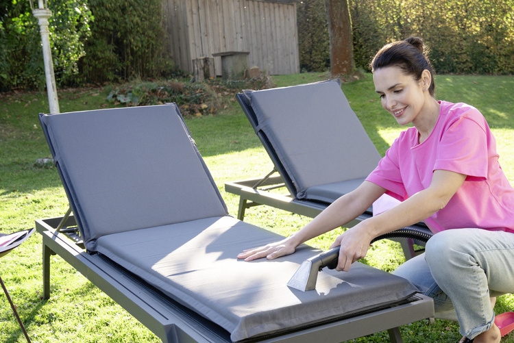 Nettoyer le mobilier de jardin en tissu Une femme nettoie les coussins en tissu de ses chaises longues de jardin