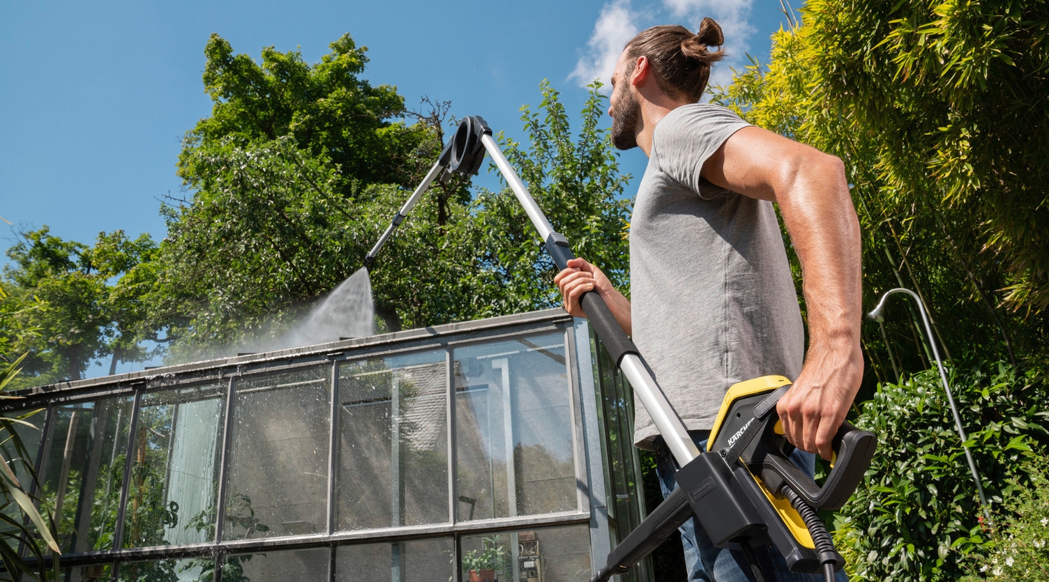 Un homme nettoie sa véranda avec un nettoyeur haute pression et une lance télescopique