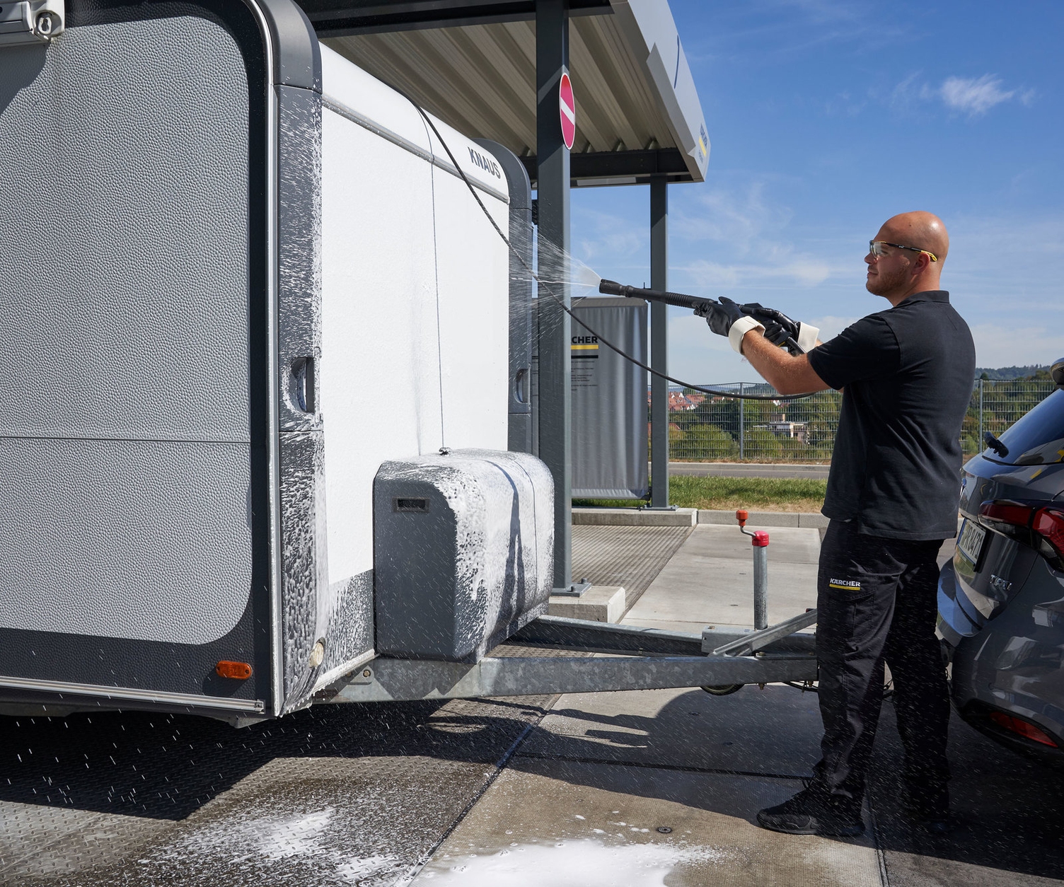 Wohnwagen reinigen Ein Mann reinigt die Vorderseite seines Wohnwagens mit einem Kärcher Hochdruckreiniger