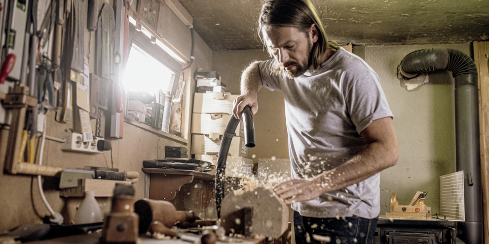 Un homme aspire sur son établi de bricolage avec un aspirateur eau et poussières Kärcher