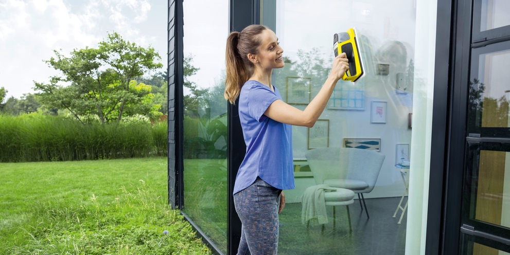 Une femme nettoie sa véranda avec un pulvérisateur vibrant Kärcher