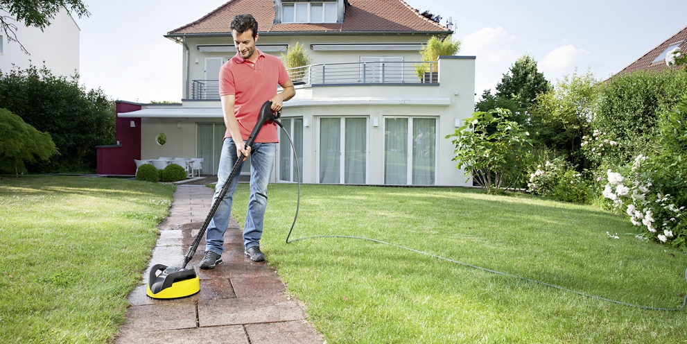 Nettoyer les pavés avec un nettoyeur haute pression et un nettoyeur de surface Un homme nettoie les pavés devant sa maison avec un nettoyeur haute pression et un nettoyeur de surface Kärcher