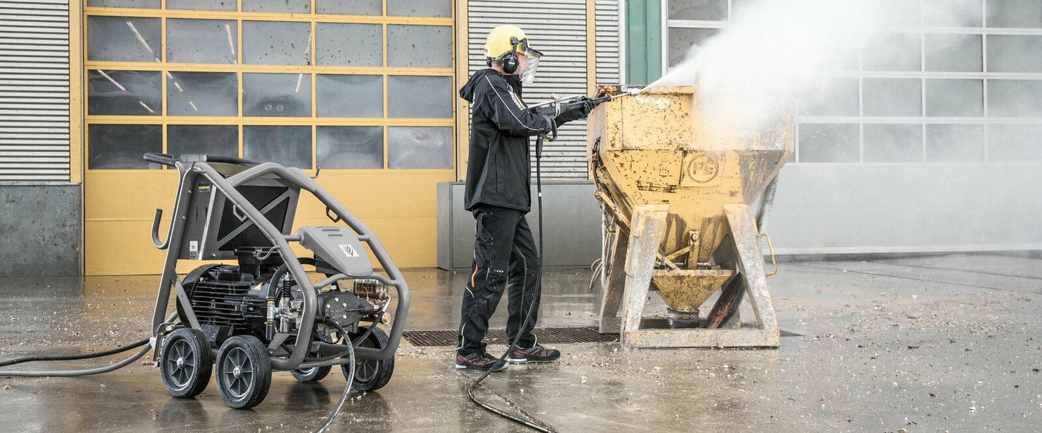 eine Person in Schutzkleidung reinigt mit einem Kärcher Höchstdruckreiniger eine Schalung