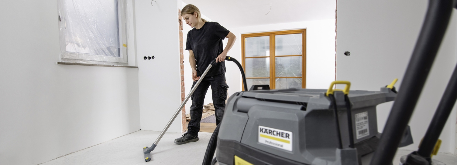Eine Person reinigt mit einem Kärcher Nass-/Trockensauger eine fertige Baustelle