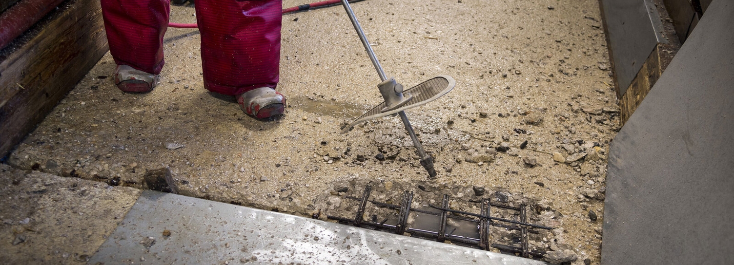 Vor der Betonsanierung Material genau prüfen Eine beschädigte Stelle im Beton wird bearbeitet