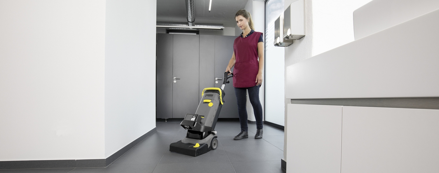 Eine Person reinigt den Fußboden einer Sanitäranlagen