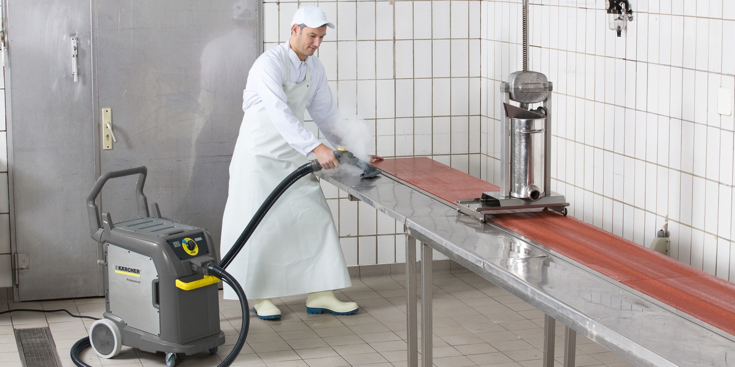 Ein Mann in weißer Arbeitskleidung reinigt eine Arbeitsfläche mit einem Kärcher Dampfsauger