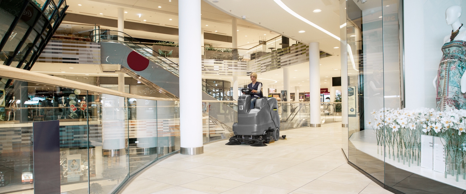 Eine Person sitzt auf einer Kehrmaschine und reinigt ein Einkaufszentrum