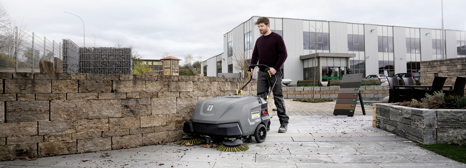 Eine Person reinigt mit einer Kehrmaschine einen Aussenbereich