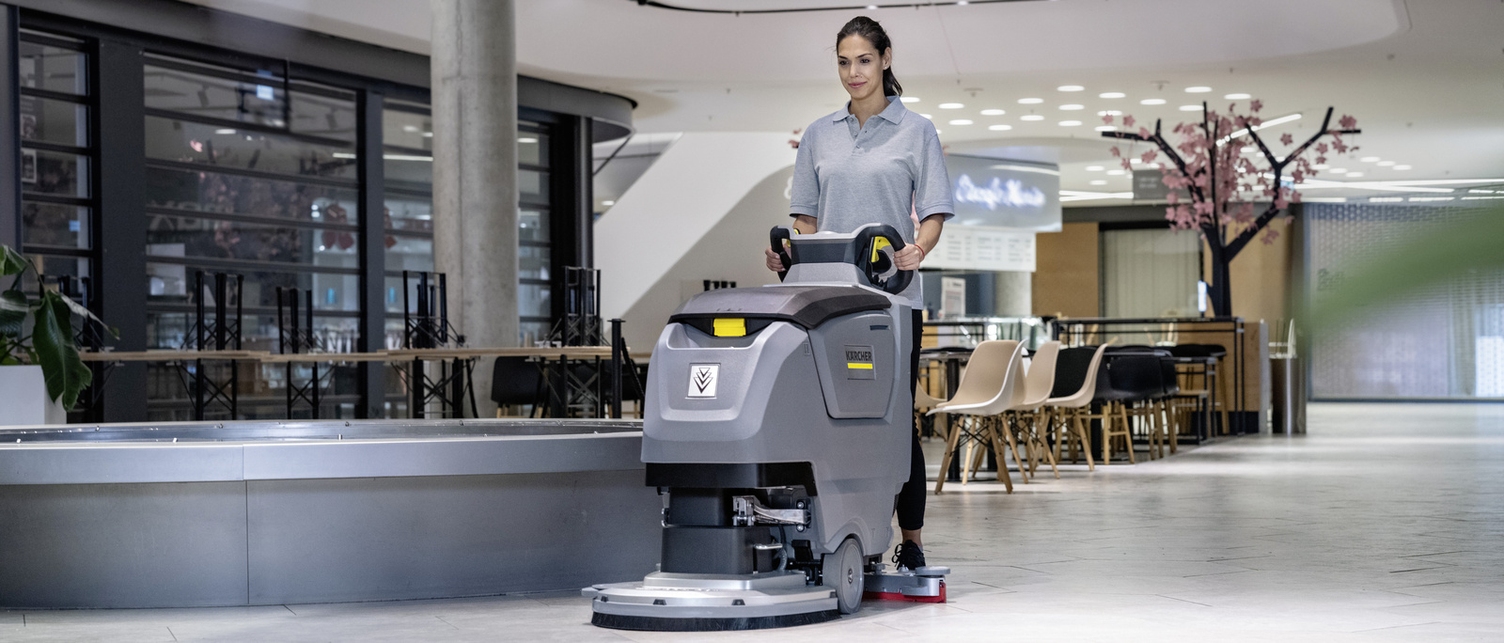 Eine Person bedient eine Scheuersaugmaschine von Kärcher