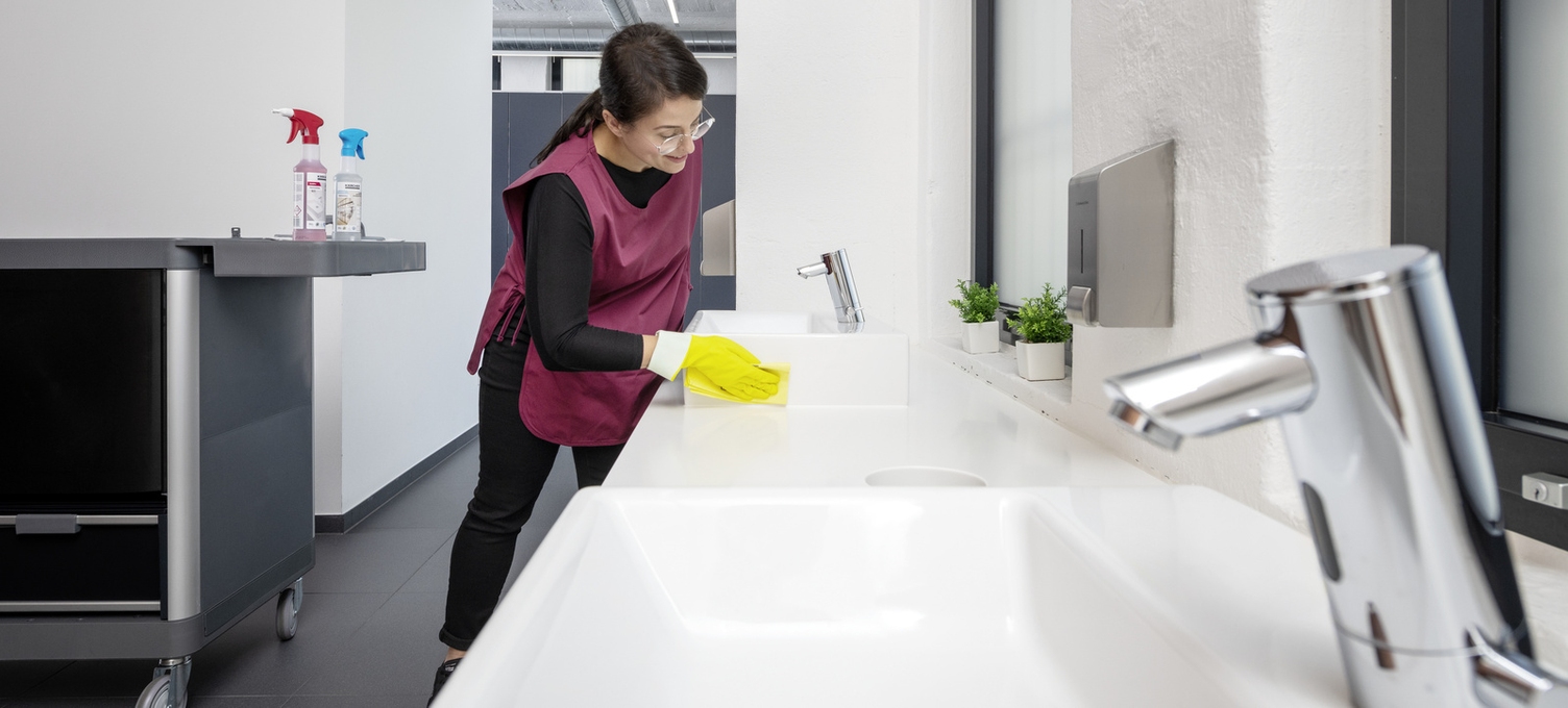 Eine Person reinigt mit einem Microfasertuch ein Waschbecken