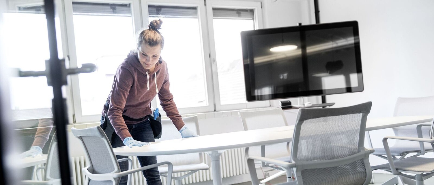 Eine Frau reinigt einen Tisch