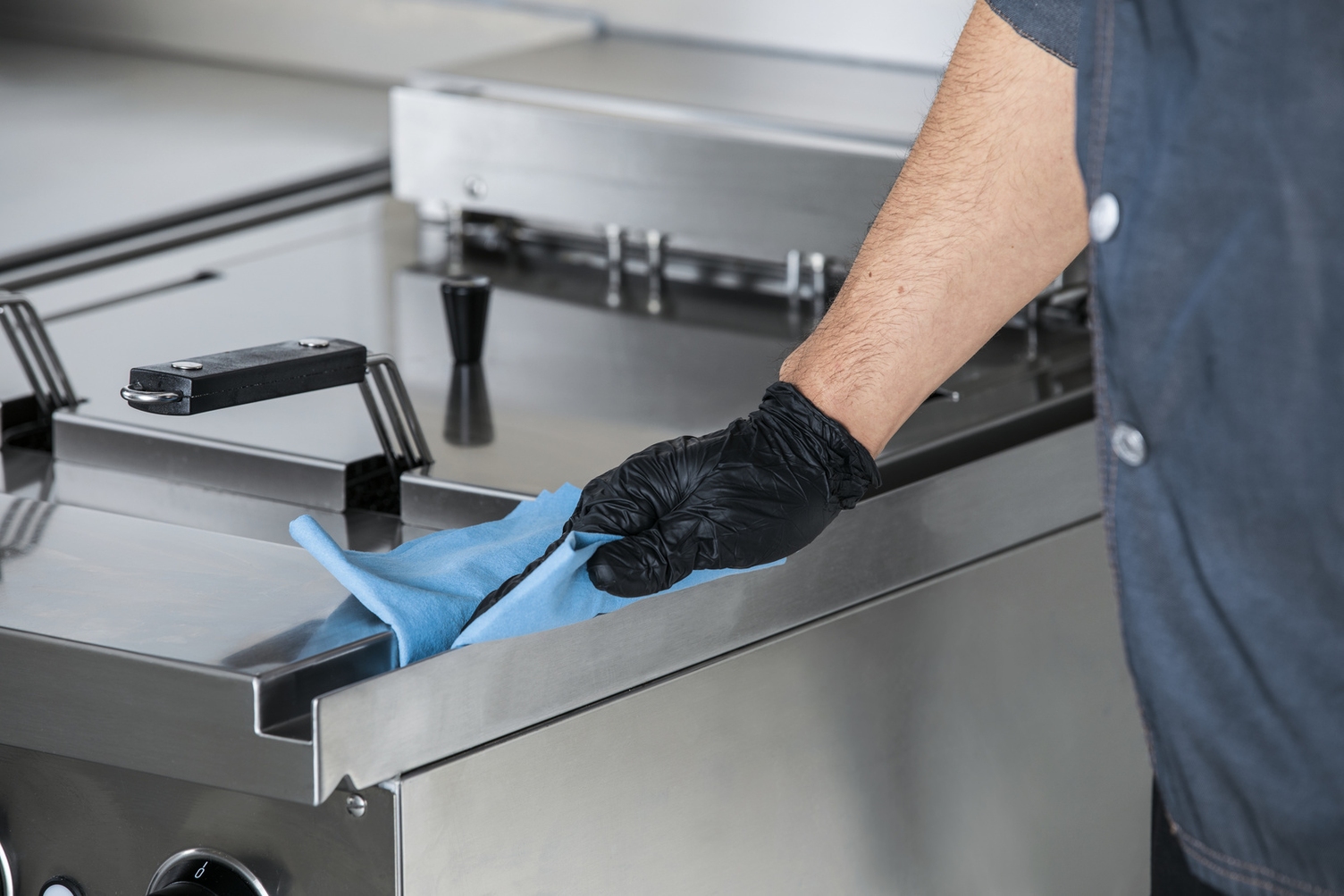 Person desinfiziert manuell Gastroküche