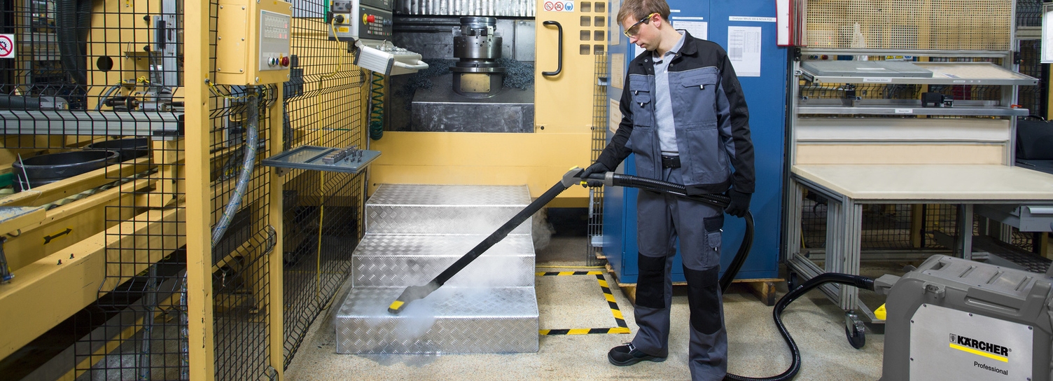 Ein Mann säubert mit einem Dampfreiniger die Treppe einer Lackieranlage
