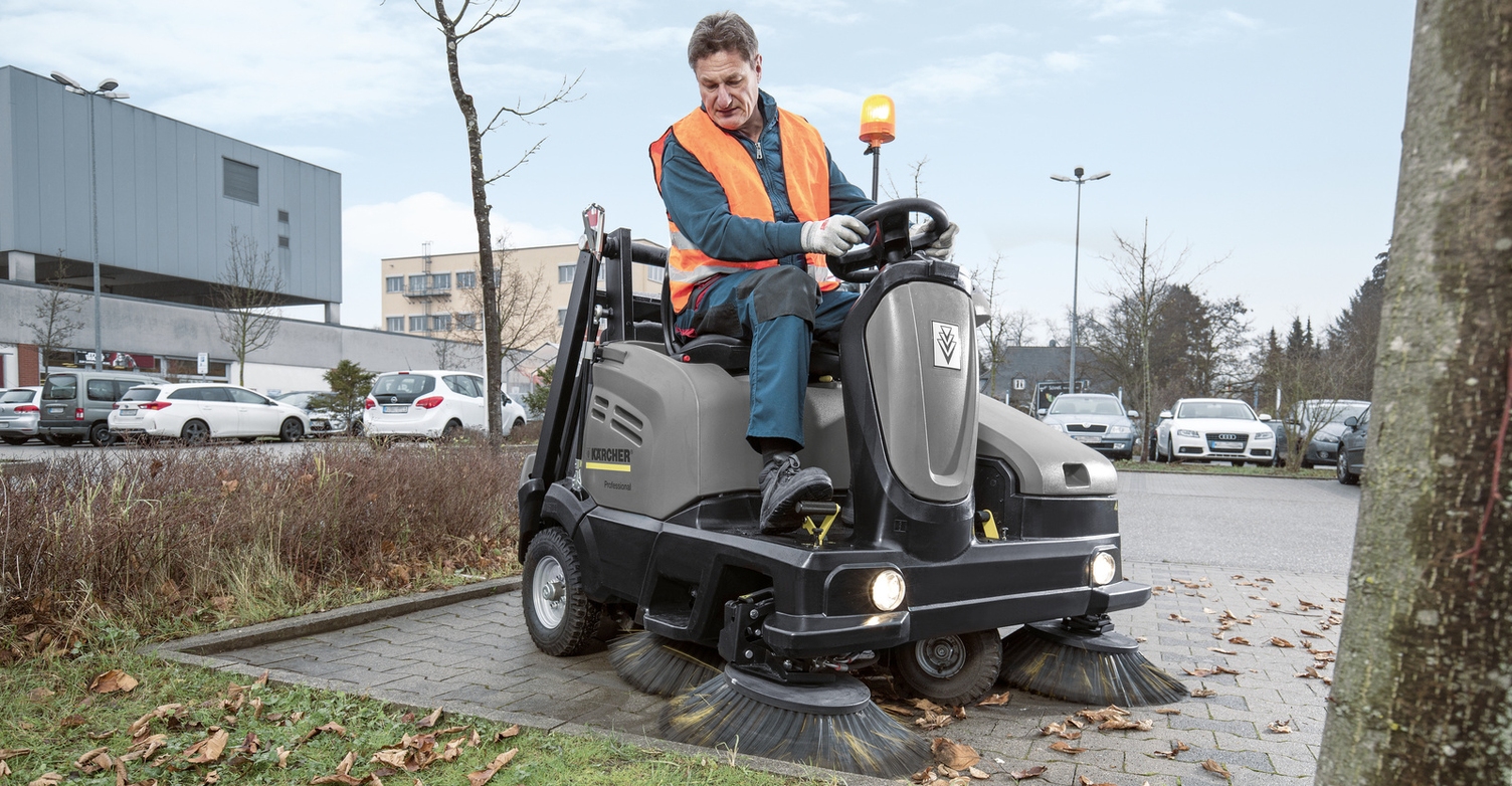 Eine Person reinigt einen Parkplatz mit einer Kehrmaschine