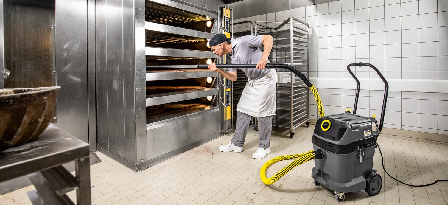 Das nötige Zubehör Ein Mann saugt mit einem Kärcher Sauger den Backofen aus
