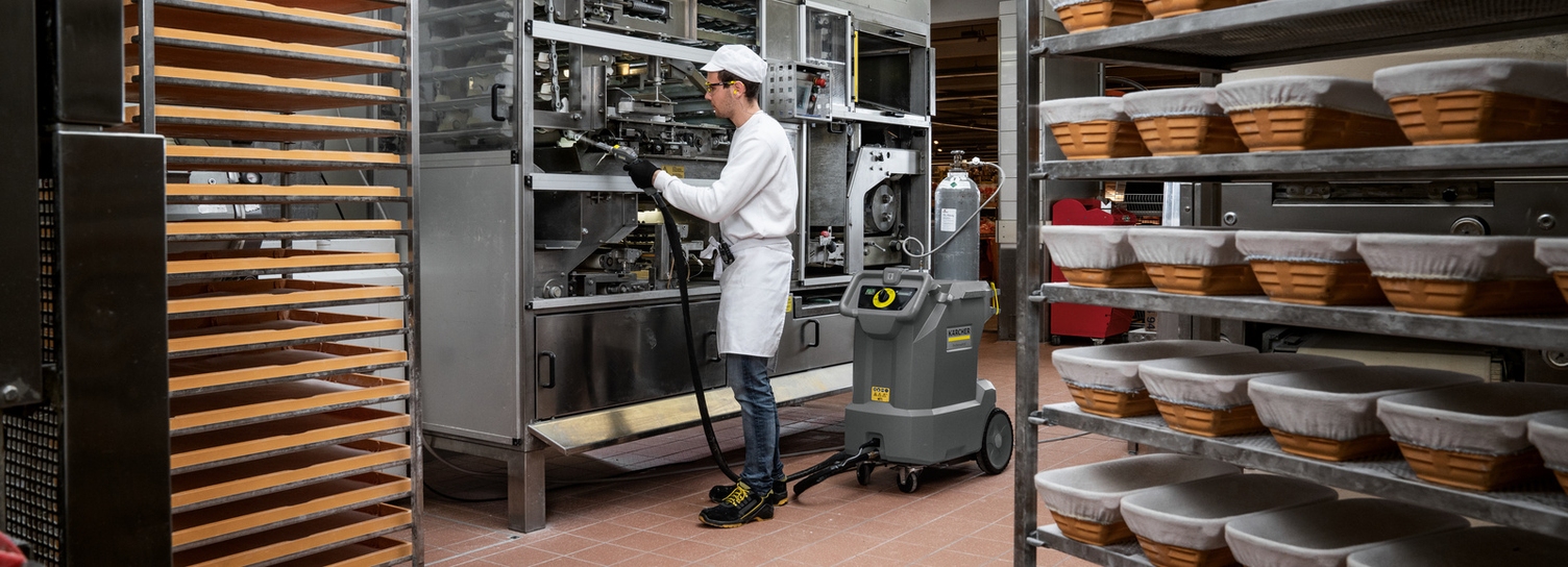 Maschinenreinigung in der Bäckerei Ansicht eines Bäckers, der das Innenleben einer Maschine mit einem Kärcher Trockensauger reinigt.