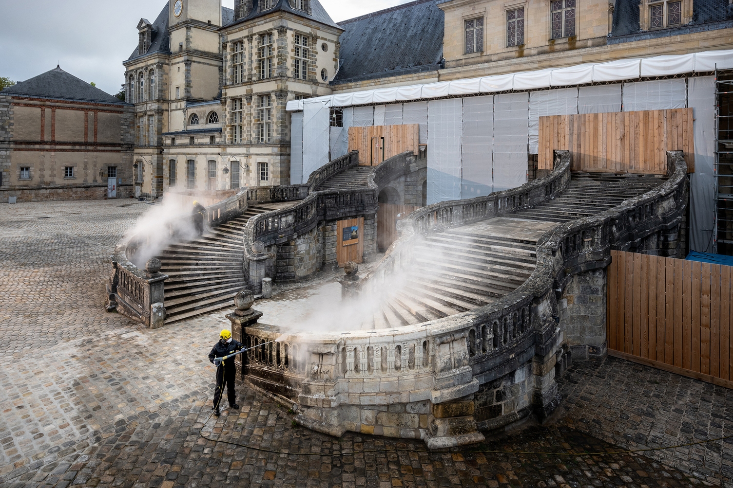 Eine Person reinigt eine alte Treppe mit einem Hochdruckreiniger