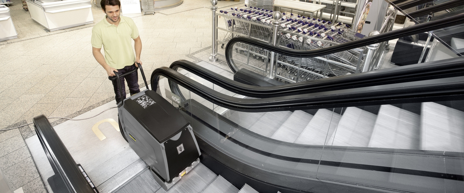 Ein Mann säubert mit einem Rolltreppenreiniger eine Rolltreppe.