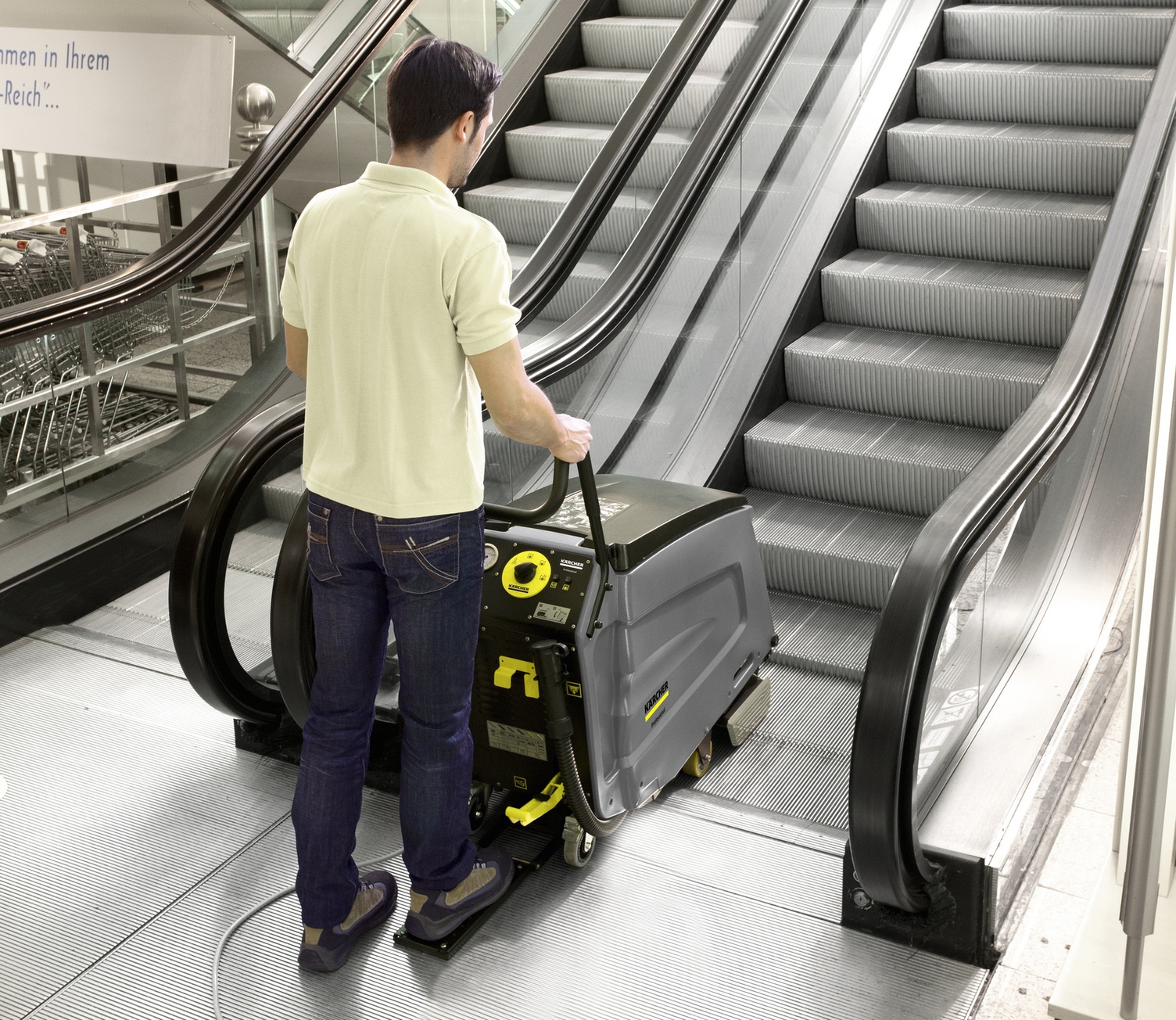 Ein Mann säubert mit einem Rolltreppenreiniger eine Rolltreppe.