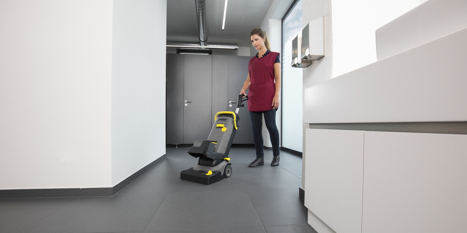 Eine Person bedient einen Elektrobesen in einer Sanitäranlage