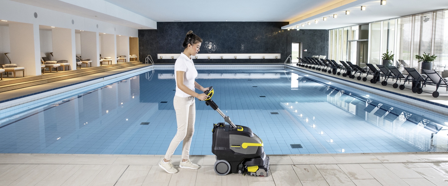 Eine Person reinigt den Beckenrand eines Schwimmbades