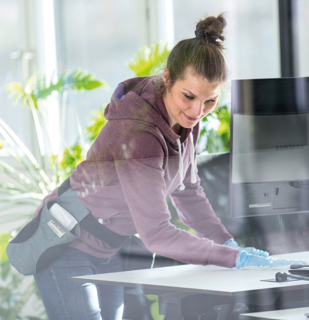 Person desinfiziert Schreibtisch mit manuellem Kärcher Equipment