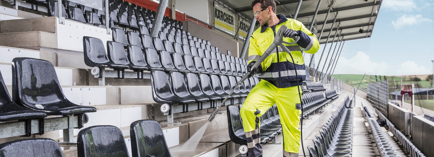 Hochdruckreiniger im Einsatz Ein Mann säubert mit einem Hochdruckreiniger von Kärcher eine Tribüne