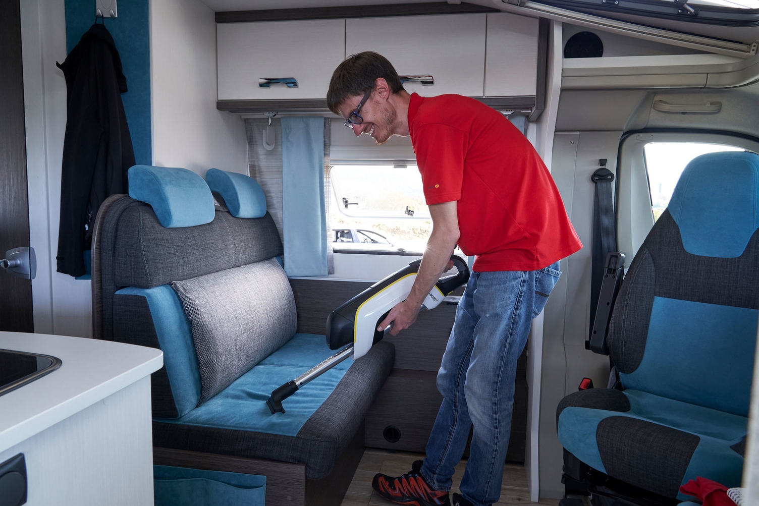 Ein Mann reinigt die Polster im Wohnmobil mit einem Kärcher Sauger 