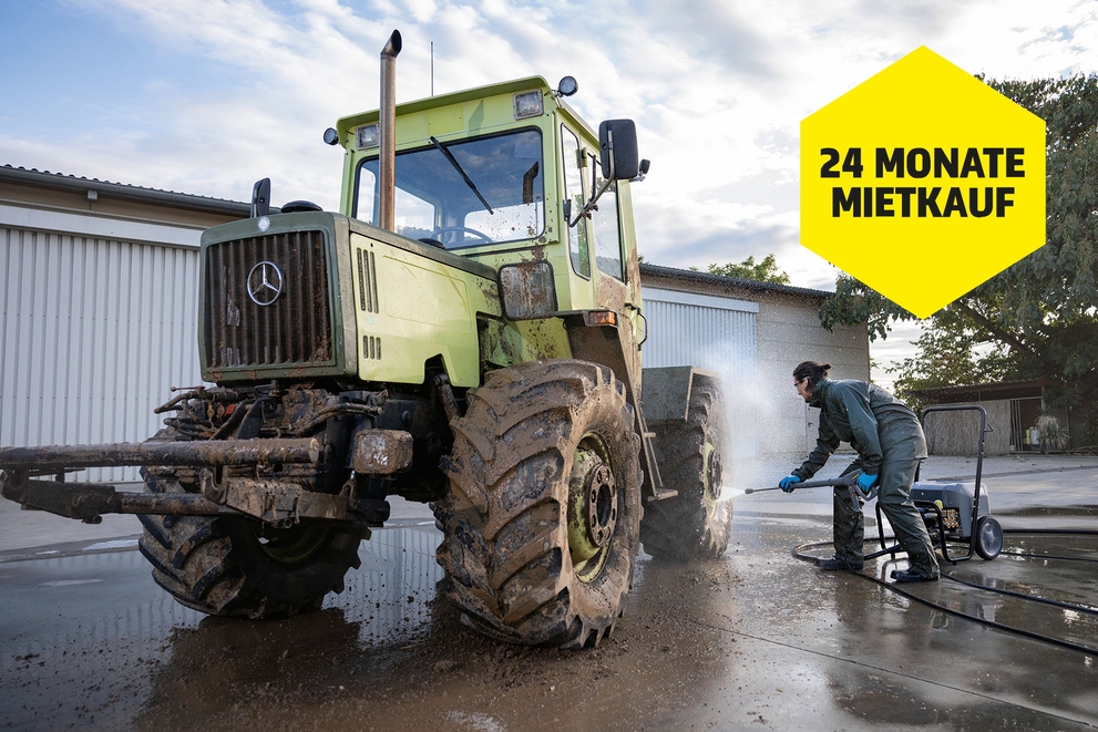 Mann mit Hochdruckreiniger bei der Reinigung eines Traktors Mann mit Hochdruckreiniger bei der Reinigung eines Traktors