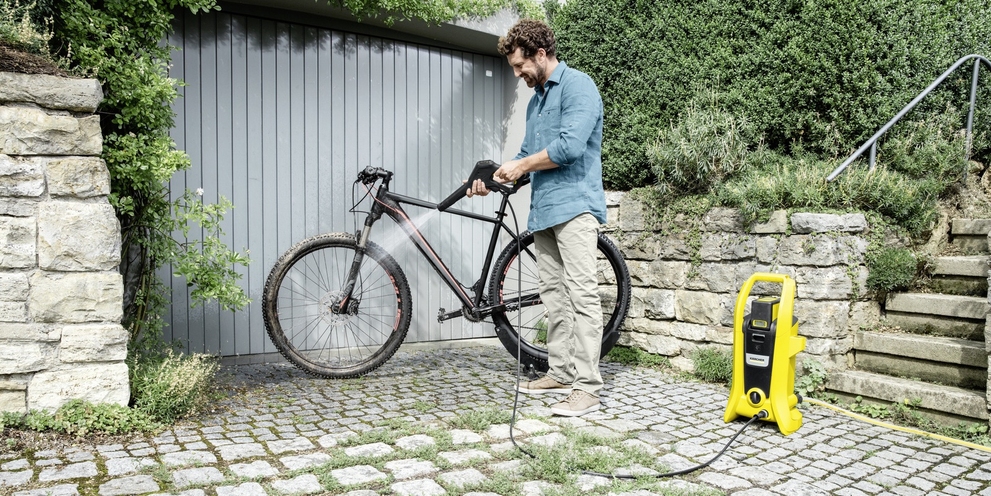 Fahrradreinigung mit Akku-Hochdruckreiniger Mann reinigt Fahrrad mit Akku-Hochdruckreiniger