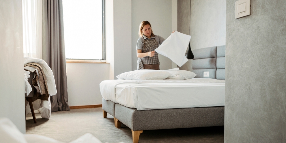 Eine Frau kümmert sich um das Hotelbett