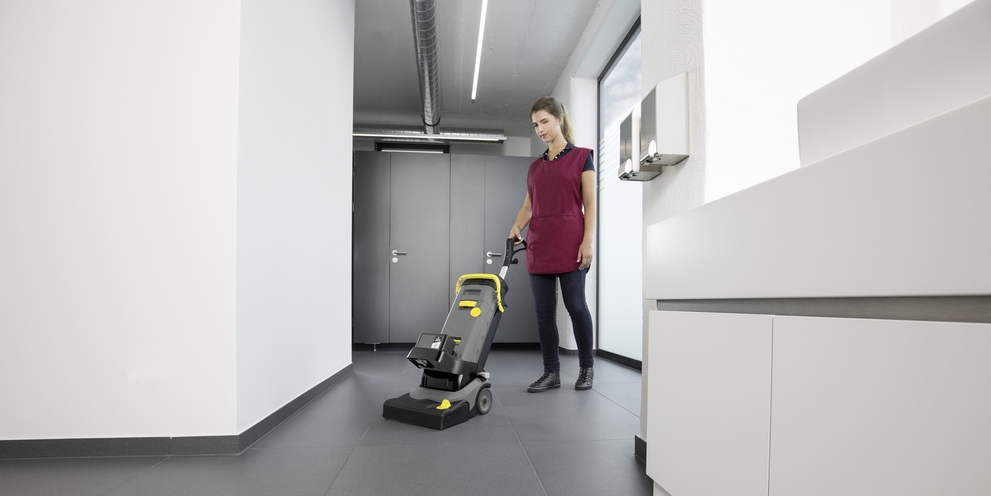 eine Person reinigt den Fußboden eines Umkleideraums