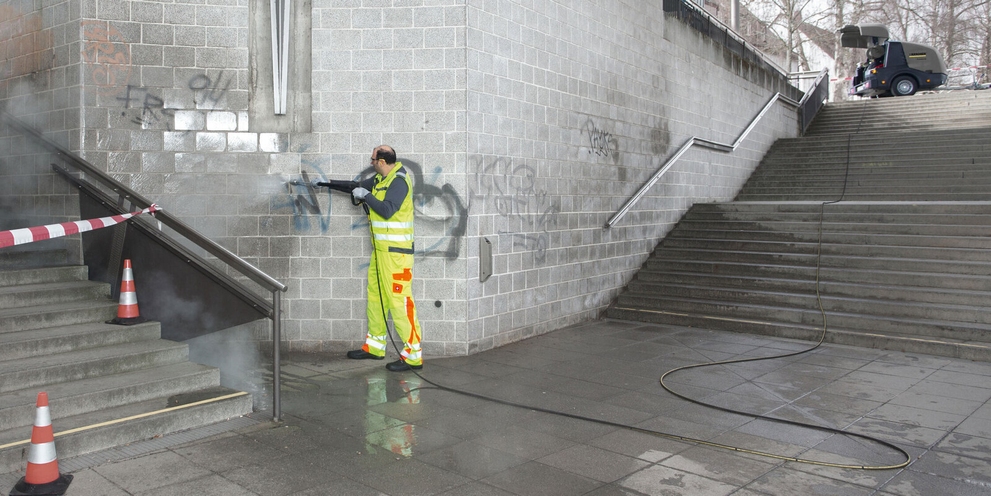 Eine Person entfernt Graffiti mit einem Kärcher Hochdruck-Trailer