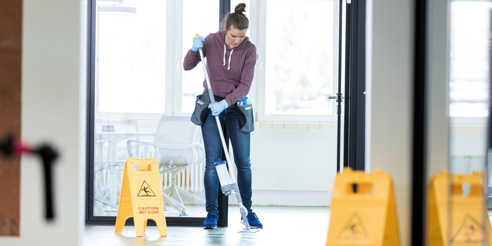 Person reinigt Fußboden manuell mit Kärcher Equipment