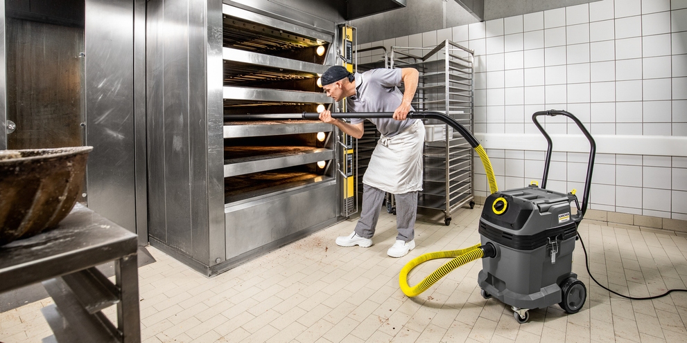 Eine Person reinigt einen Backofen mit einem Bäckersauger