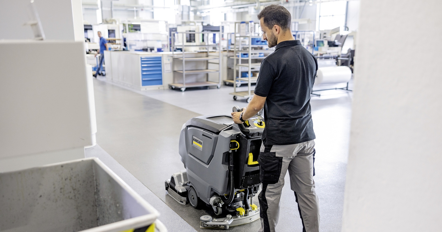 A man cleans the floor with a Kärcher walk-behind scrubber-dryer