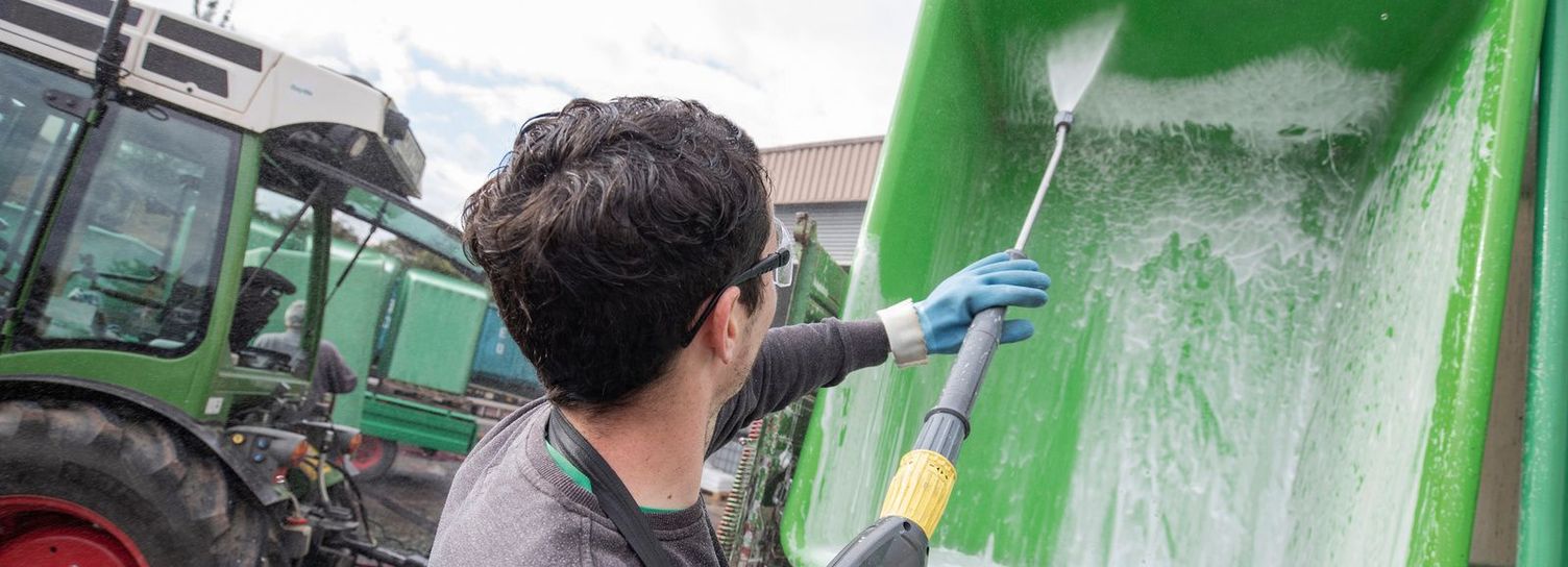 A man cleans a green box with a Kärcher high-pressure cleaner