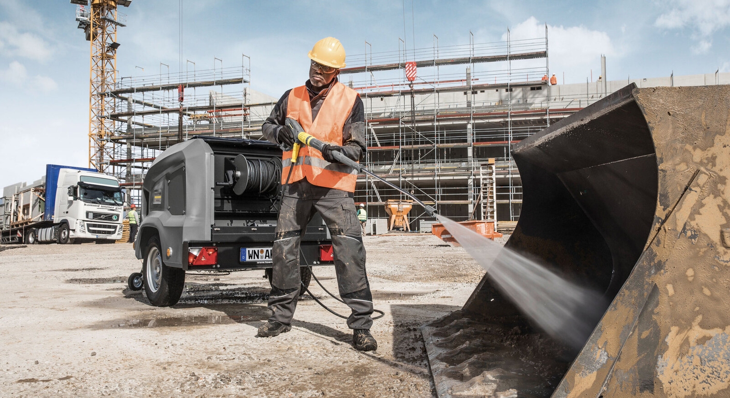 a person uses a high-pressure cleaner to clean an excavator bucket