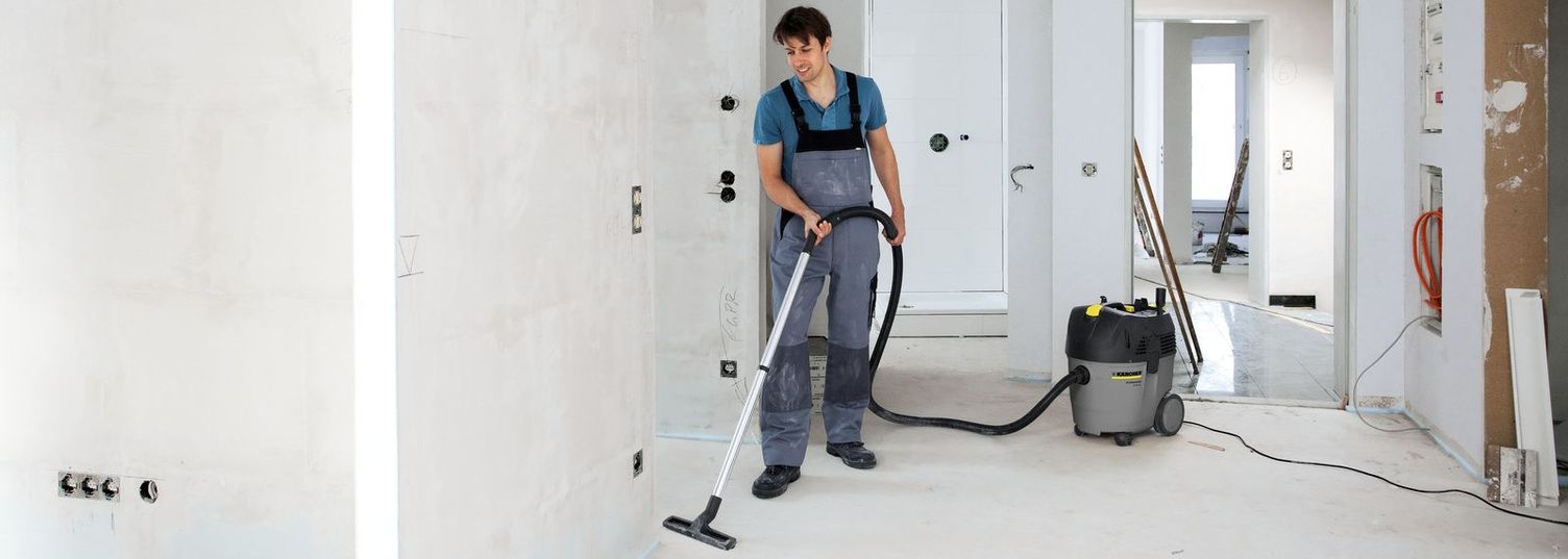 Post construction cleaning using a powerful industrial vacuum cleaner A person cleans the unfinished floor with a Kärcher Wet And Dry Vacuum Cleaner