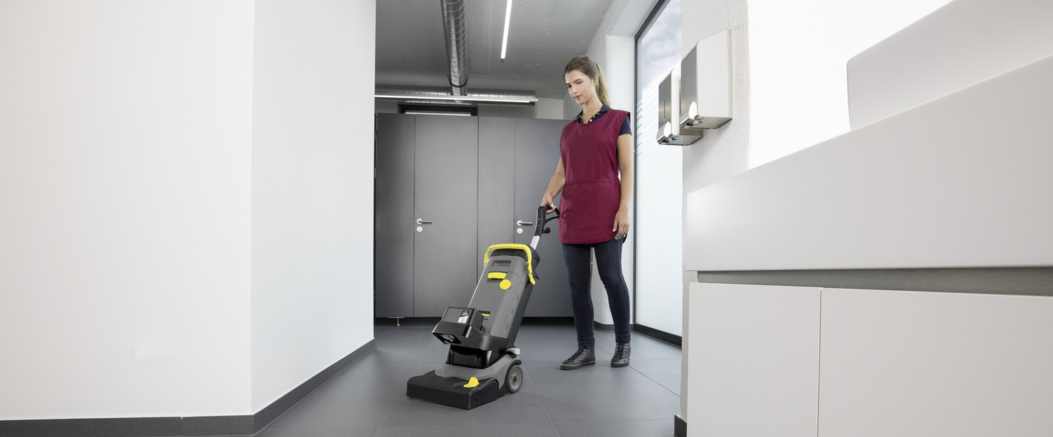 A person cleans a sanitary area with a scrubber dryer