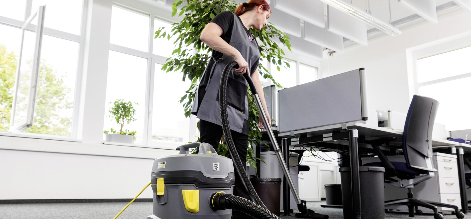 A person is cleaning an office with a Kärcher vacuum cleaner